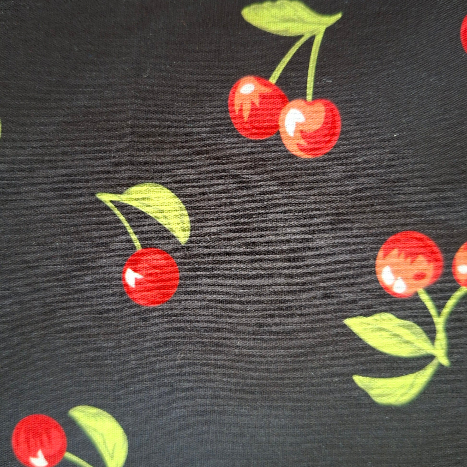 Fabric with red cherry pattern on a black background