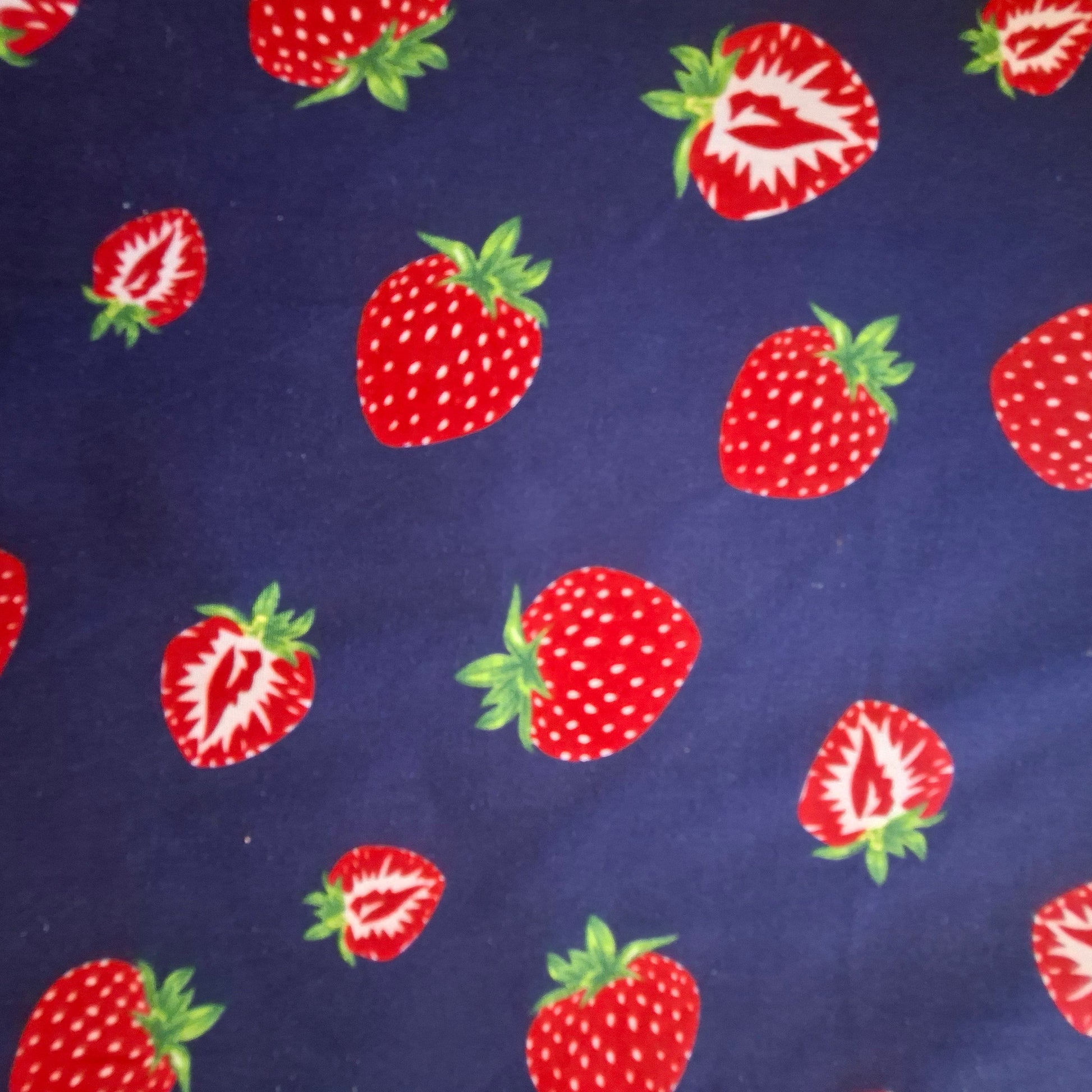 Red strawberries with green leaves on a blue fabric background
