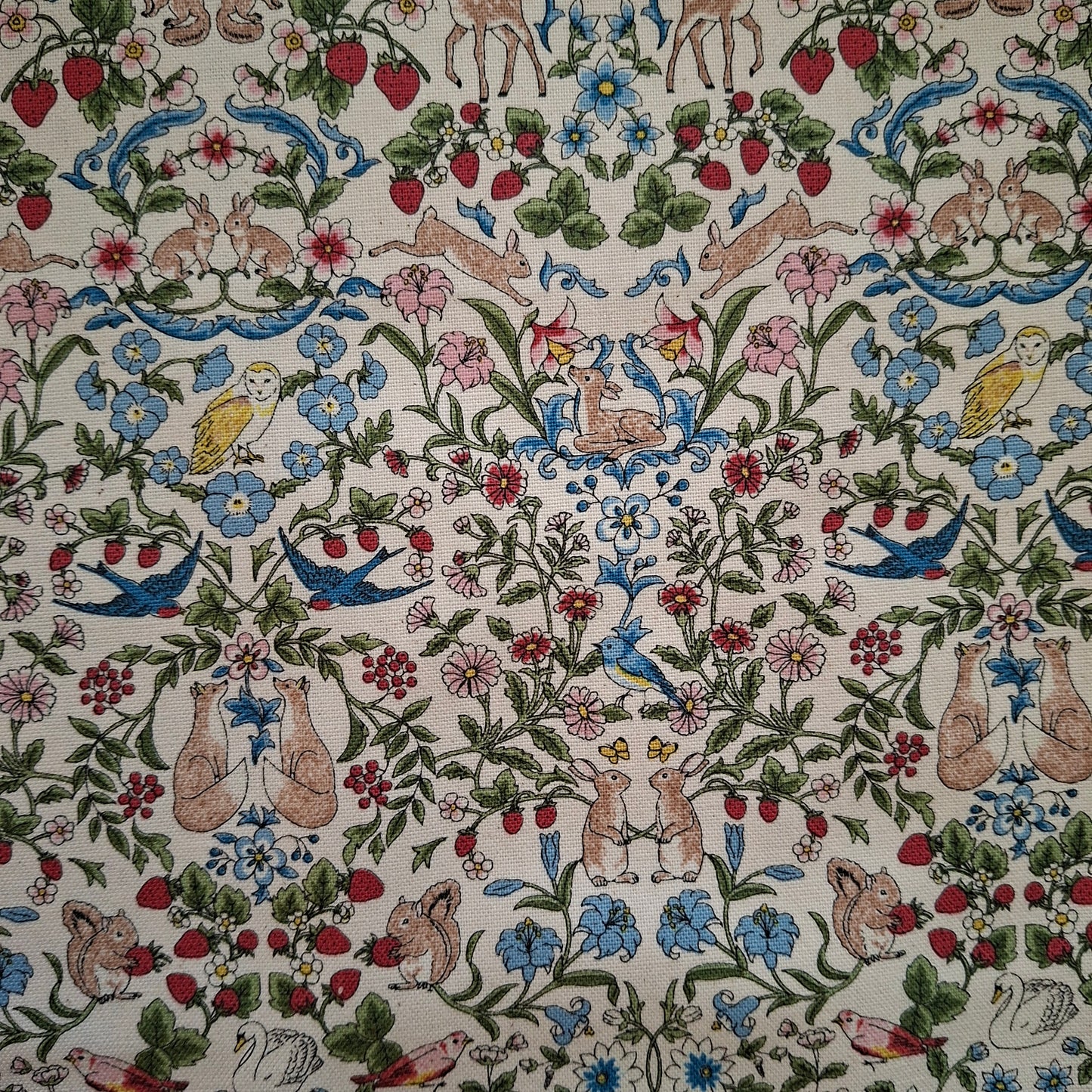Patterned fabric with animals, flowers, and birds on a beige background